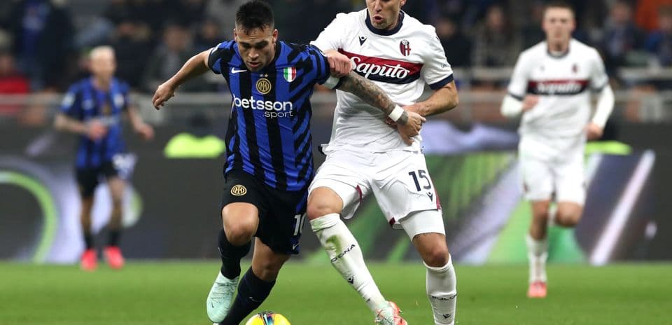 Inter player battling Bologna opponent for the ball