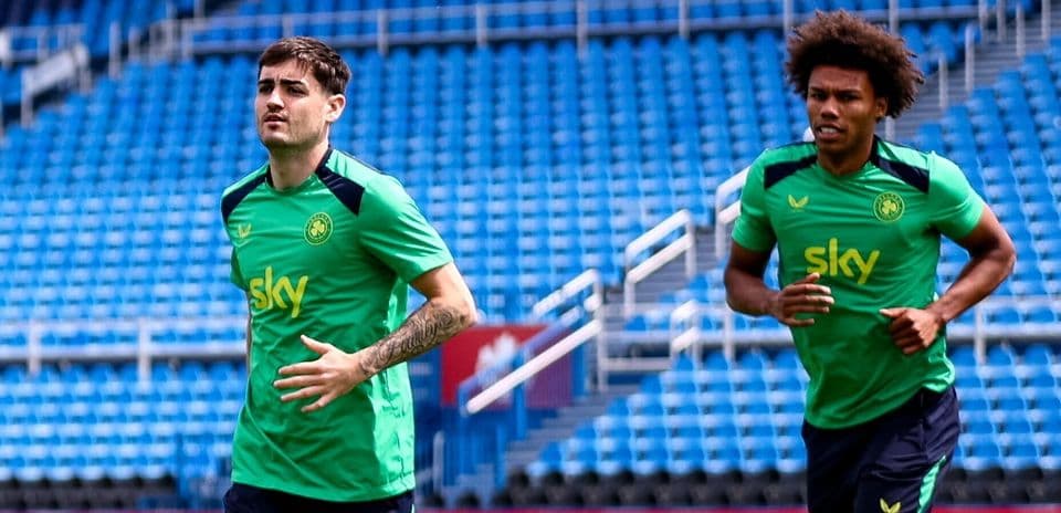 Two players jogging on training pitch at stadium