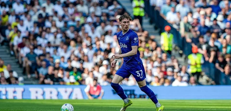 Player in blue kit running with the ball on pitch