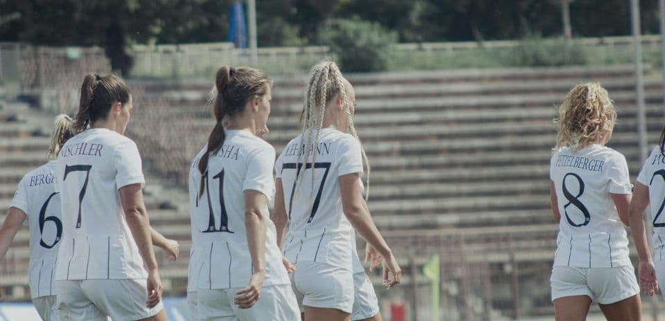 Players walking on the pitch in white jerseys