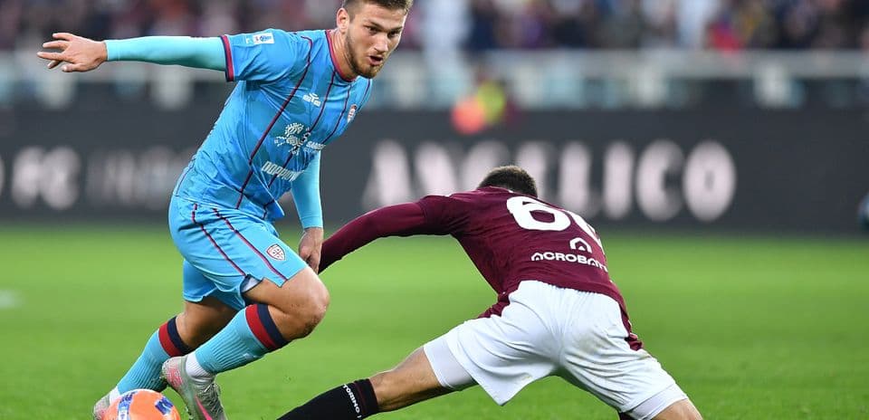 Cagliari player evading a tackle from Torino opponent