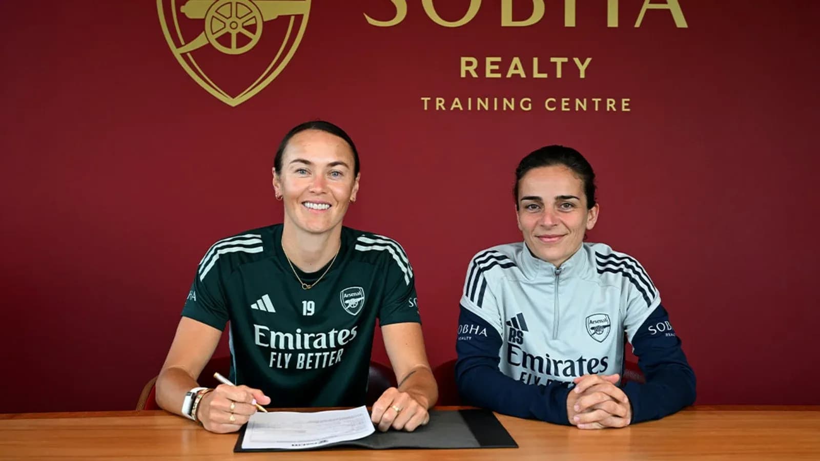 Two players signing contracts at Arsenal training centre