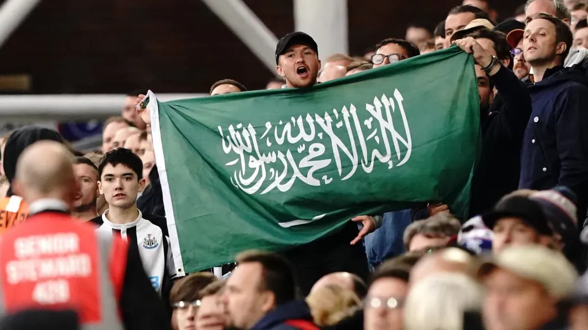 Fan holding Saudi Arabian flag in the stands