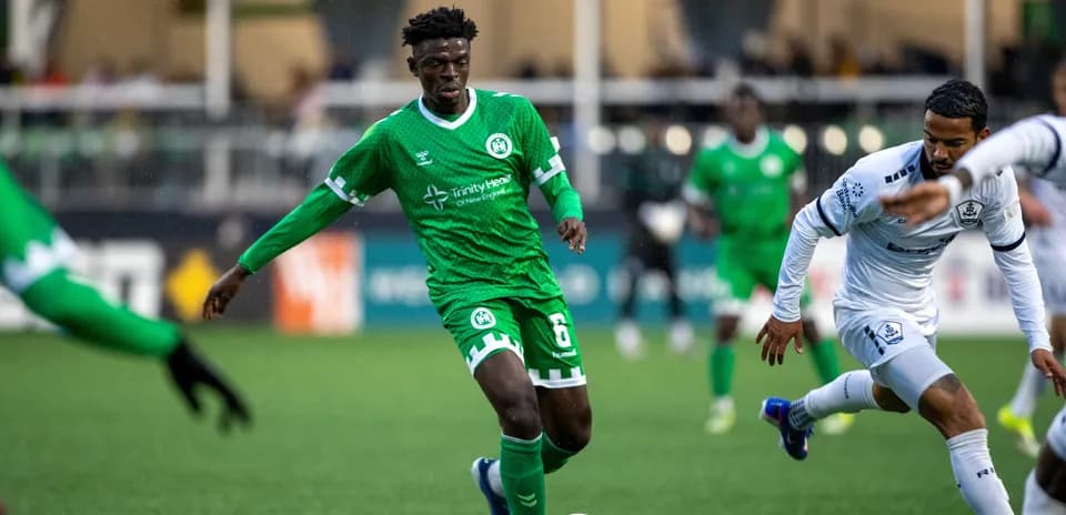 Player in green kit dribbling the ball during match