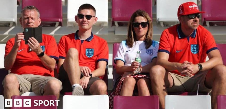 Fans wearing England jerseys sitting in stadium seats