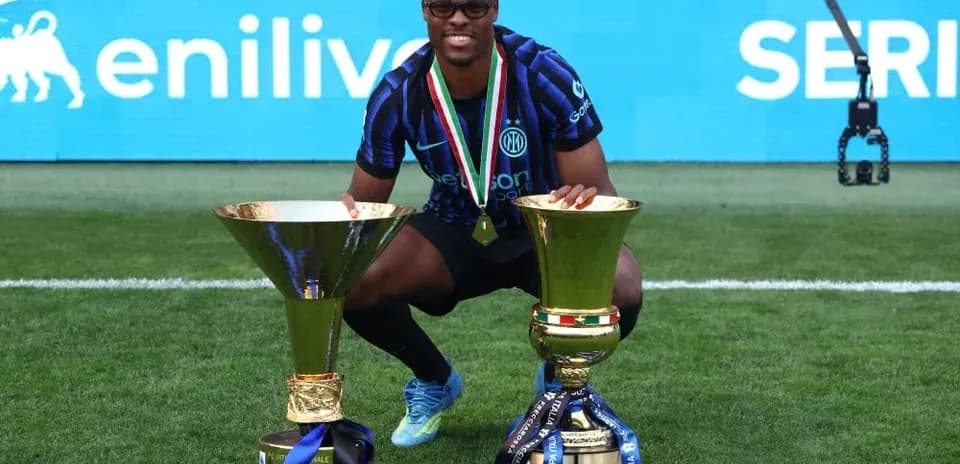Player posing with two trophies on the field