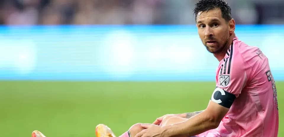 Player seated on field during match in pink jersey