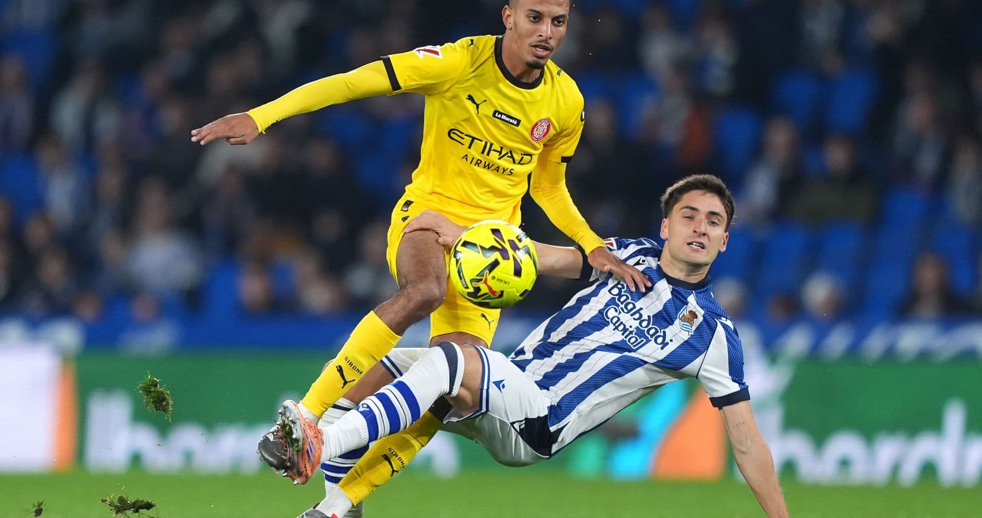Girona player challenging Real Sociedad opponent
