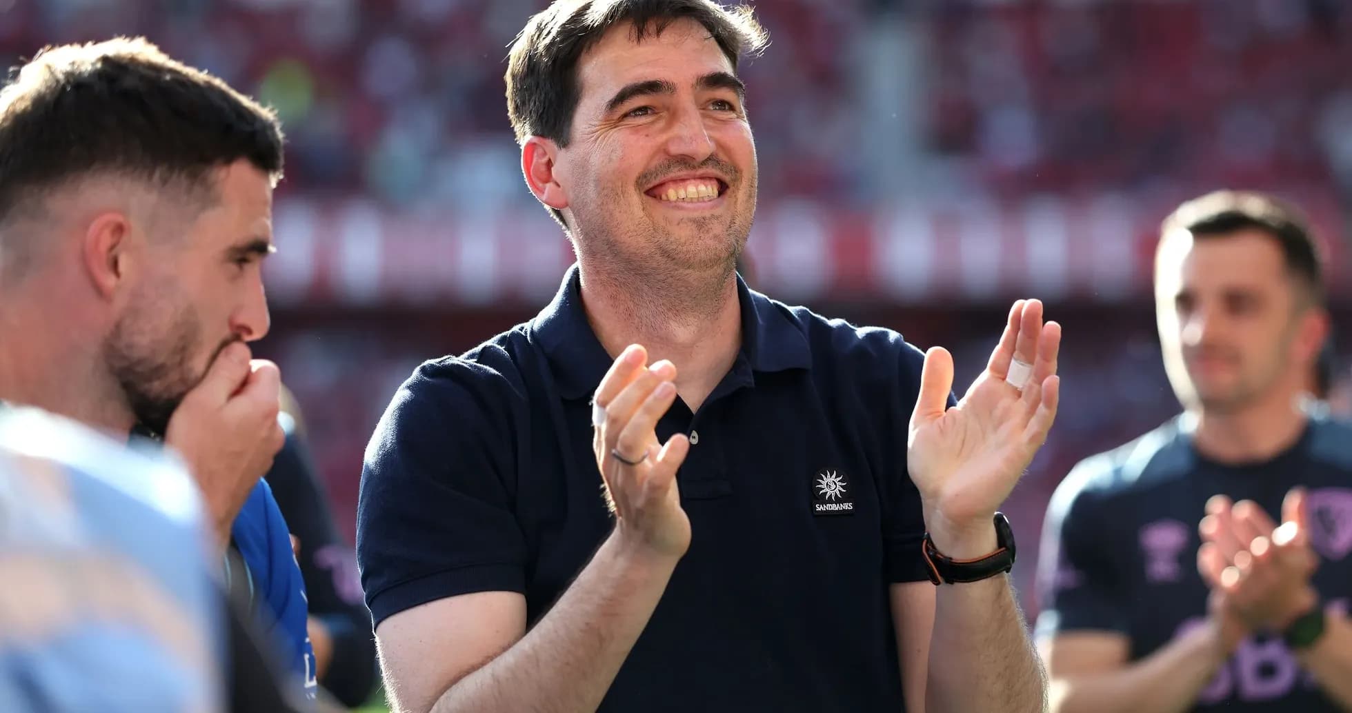 Coach applauding with players in background during match