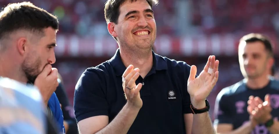 Coach applauding with players in background during match