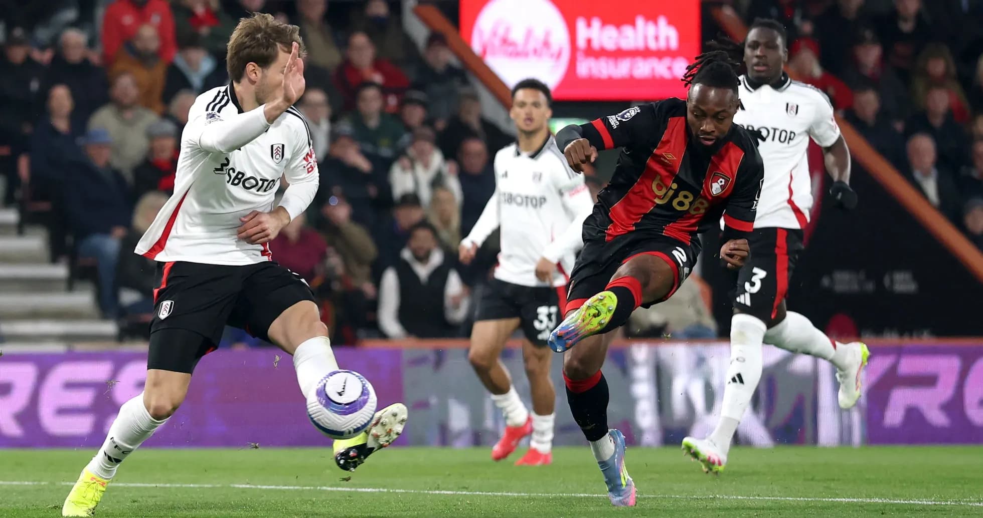 Fulham player challenges Bournemouth opponent for the ball