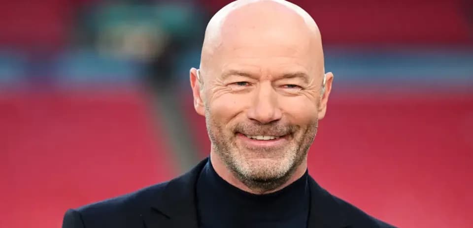 Bald man in suit smiling at stadium