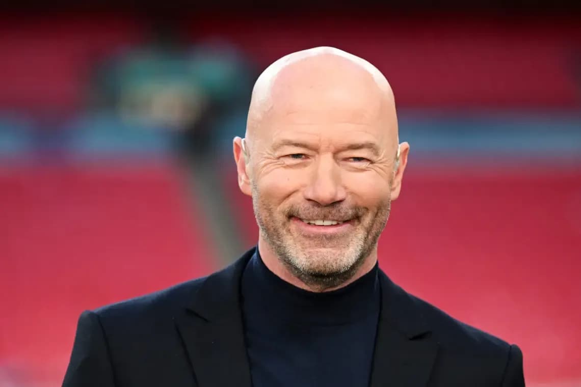 Bald man in suit smiling at stadium