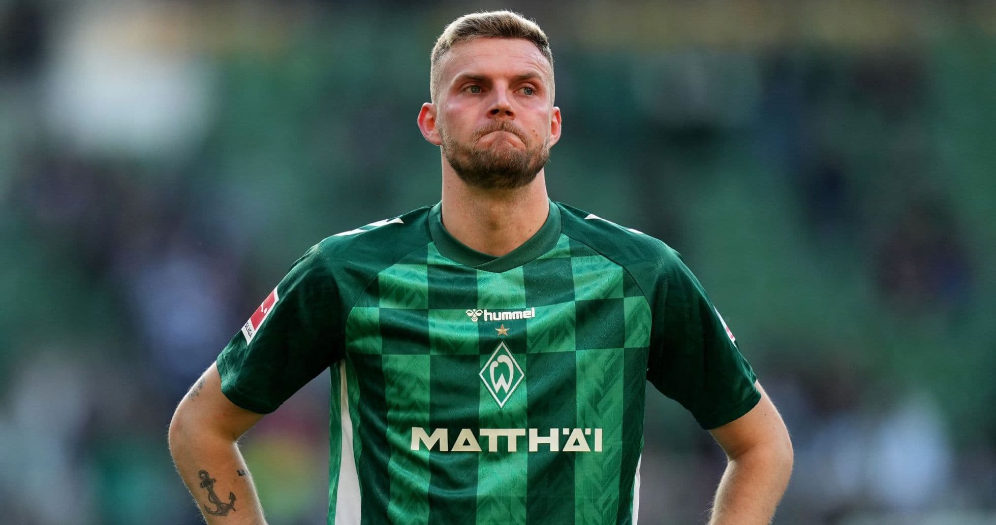 Player in green jersey looking down on field Player in green jersey looking down on field
