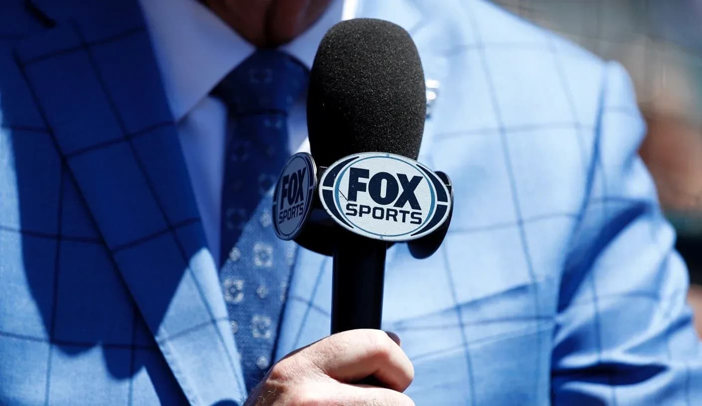 Person holding a FOX Sports microphone on blue suit Person holding a FOX Sports microphone on blue suit