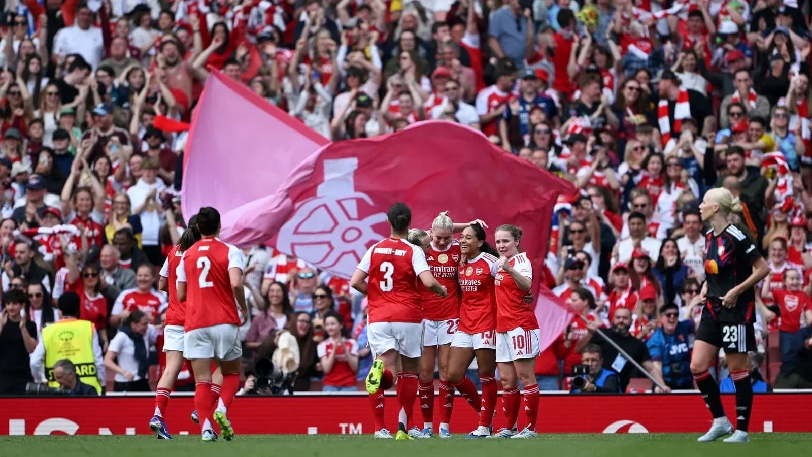 Arsenal women celebrating goal with fans in background Arsenal women celebrating goal with fans in background