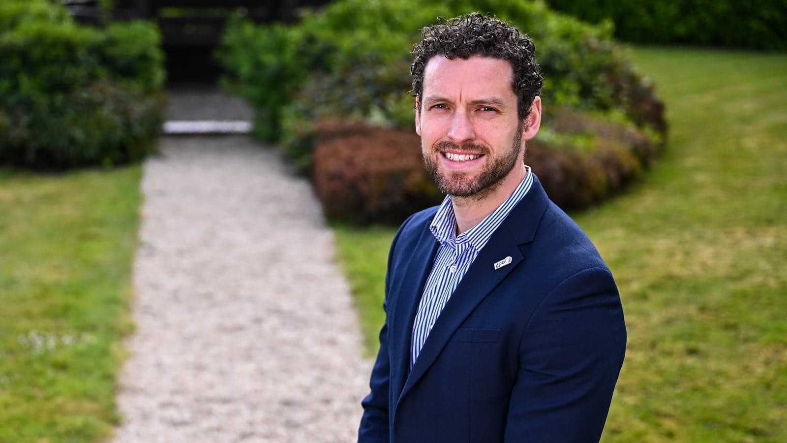 Man in suit smiling in garden setting Man in suit smiling in garden setting