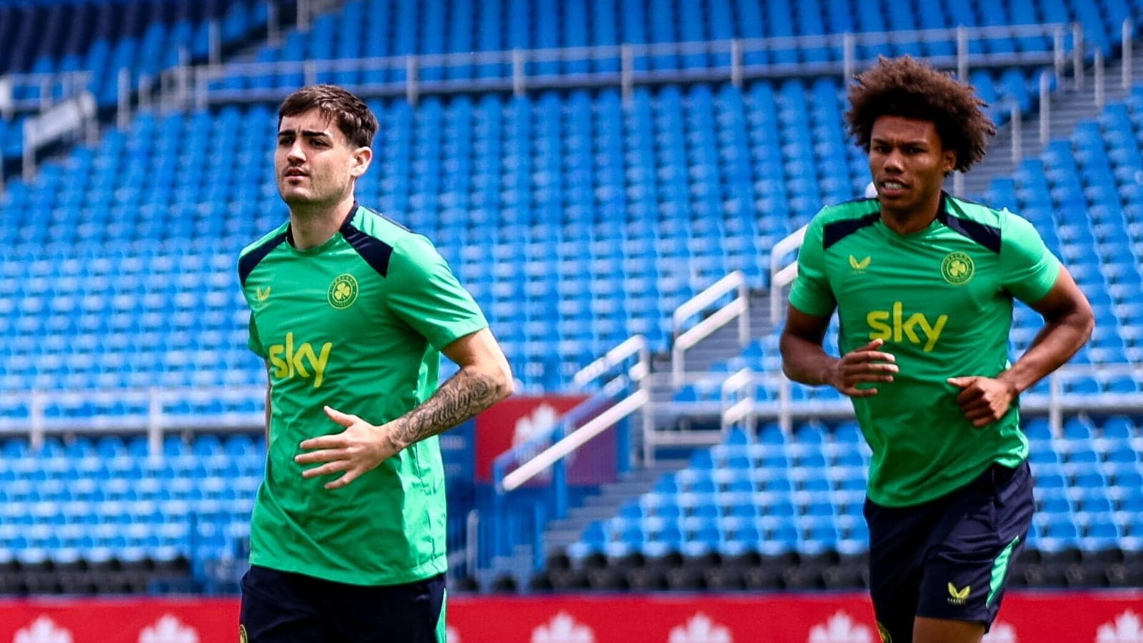 Two players jogging on training pitch at stadium Two players jogging on training pitch at stadium