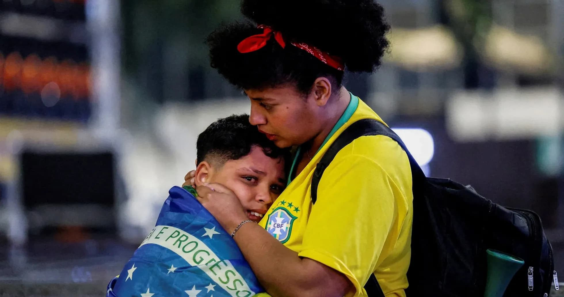 Woman comforting child wrapped in Brazilian flag Woman comforting child wrapped in Brazilian flag