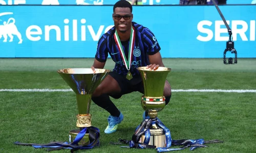 Player posing with two trophies on the field Player posing with two trophies on the field