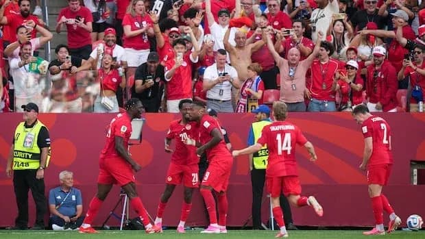 Players celebrating a goal with fans in background Players celebrating a goal with fans in background